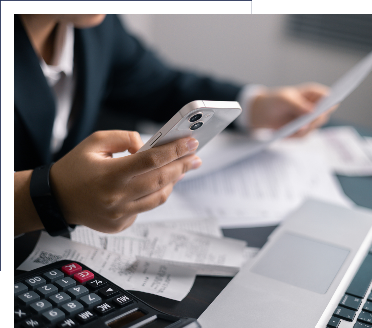 Person analyzing financial documents with calculator and smartphone.