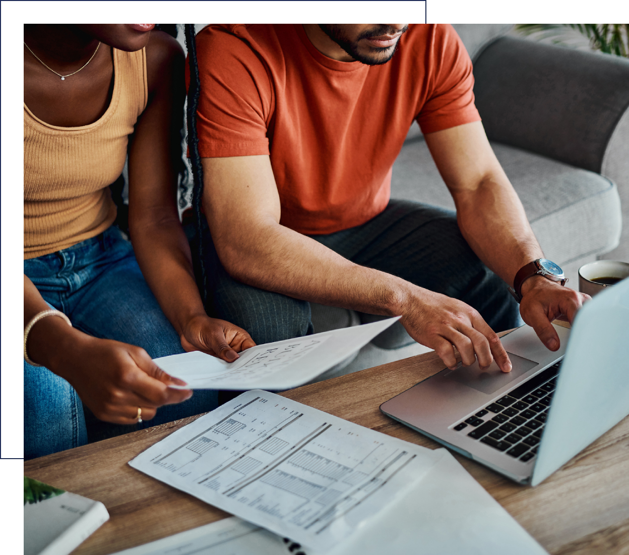 Two people working together on financial documents and a laptop.