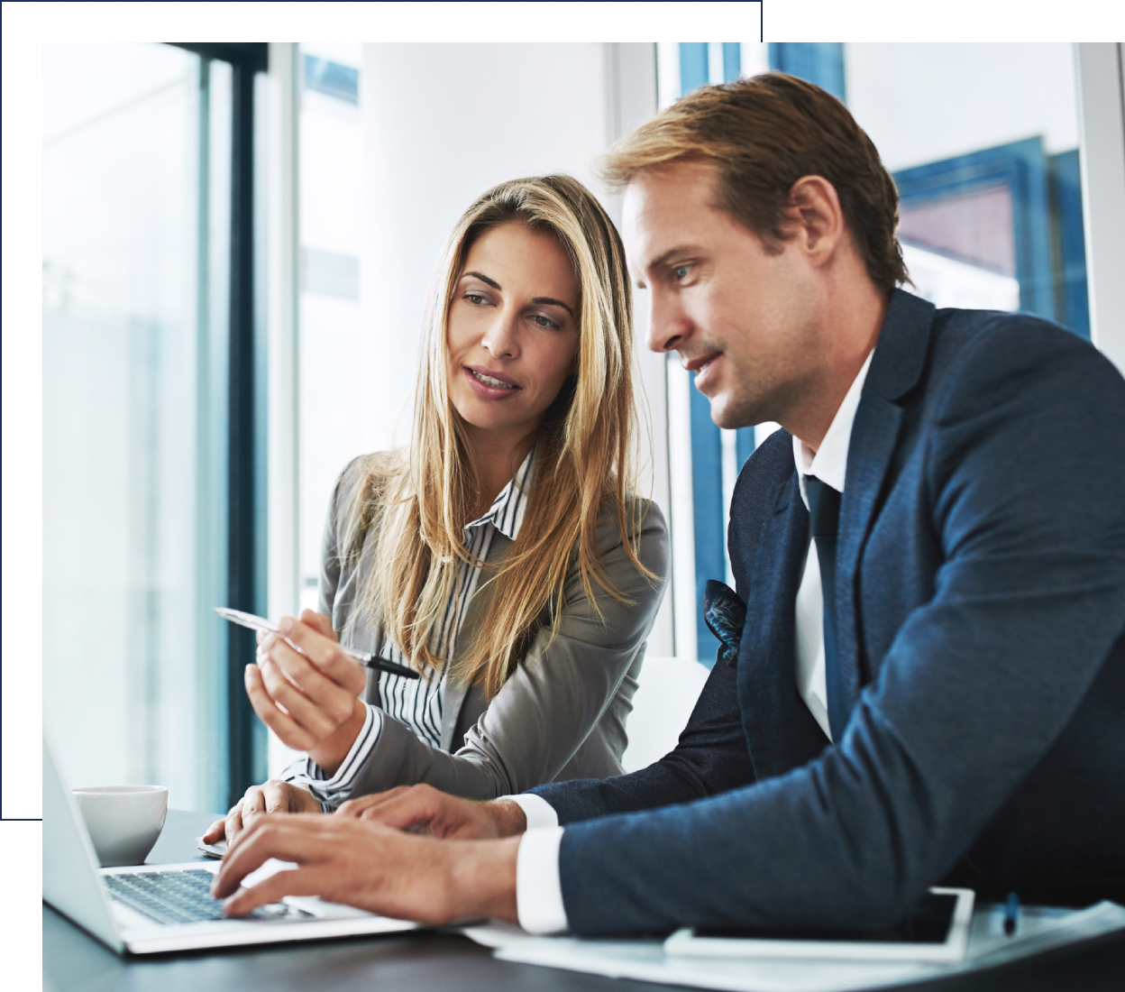 Two professionals collaborating at a laptop in an office.